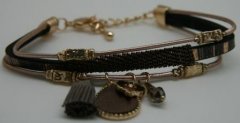 Flot sort armbnd i forskellige materialer med charms og brun bnd. Lukkes med karabinls