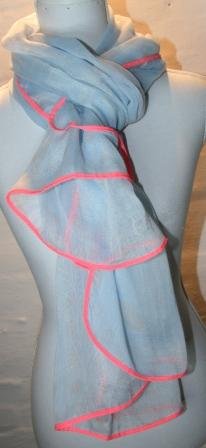 Lyseblåt tørklæde med lyst mønster, hvide prikker og pink kant. Måler 180 x 95 cm.