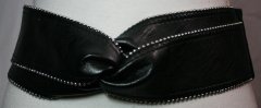 8 cm. bredt sort elastik bælte. Foran kunstlæder med nittekant, der laver en knude, bagpå elastik der lukkes med tryklåse. One Size.